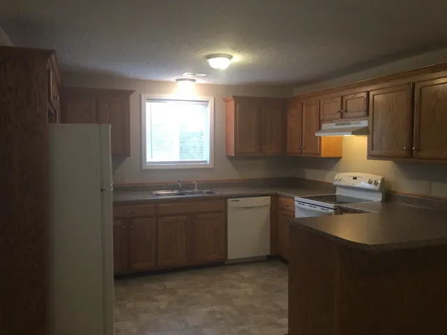 a kitchen with granite countertop cabinets stainless steel appliances a sink and a window