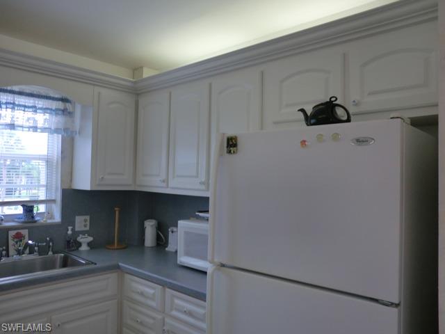 4372 27th Court Southwest, Unit 210 Naples, FL 34116 - Photo 1 of 19 a kitchen with a refrigerator and cabinets
