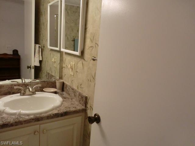 4372 27th Court Southwest, Unit 210 Naples, FL 34116 - Photo 13 of 19 a bathroom with a granite countertop sink and a mirror