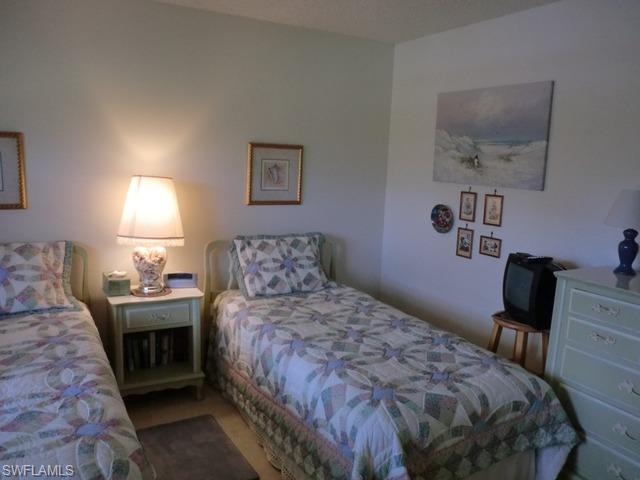 4372 27th Court Southwest, Unit 210 Naples, FL 34116 - Photo 16 of 19 a bedroom with a bed and a chair