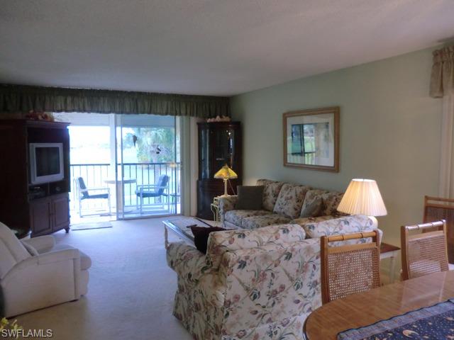 4372 27th Court Southwest, Unit 210 Naples, FL 34116 - Photo 2 of 19 a living room with furniture and a flat screen tv