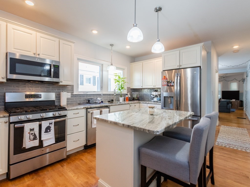 31-33 College Hill Road Somerville, MA 02144 - Photo 24 of 38 a large kitchen with stainless steel appliances granite countertop a stove a sink dishwasher a refrigerator and a dining table with wooden cabinet