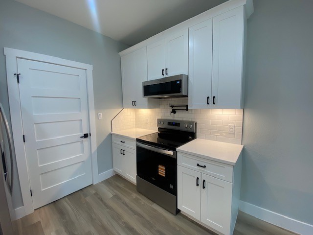 116 Field Street Luling, TX 78648 - Photo 6 of 33 A compact culinary space features modern white cabinetry and essential appliances for efficient living.