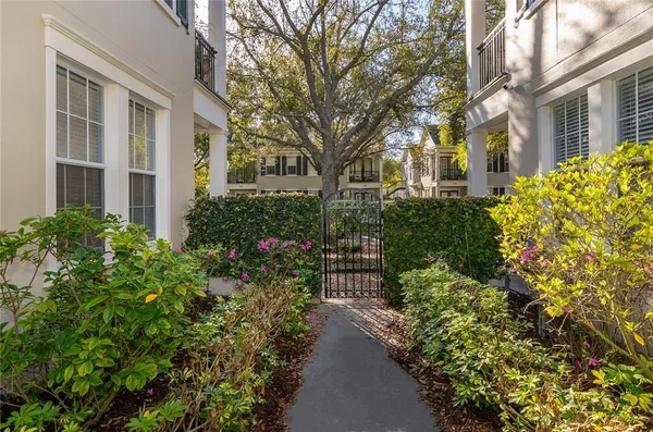 a view of a pathway with flower garden in front of house