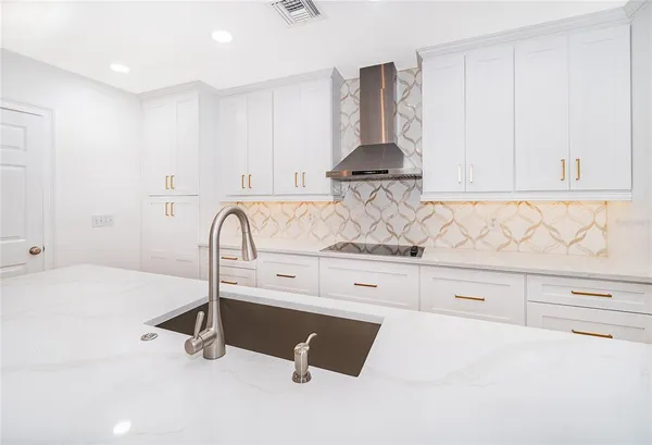 a kitchen with white cabinets and sink