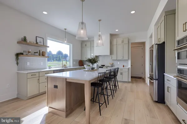 a kitchen with stainless steel appliances kitchen island granite countertop a table chairs refrigerator and sink
