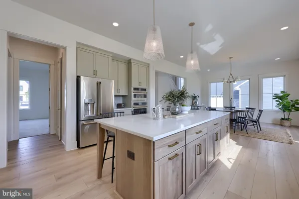a kitchen with stainless steel appliances a table chairs refrigerator and cabinets