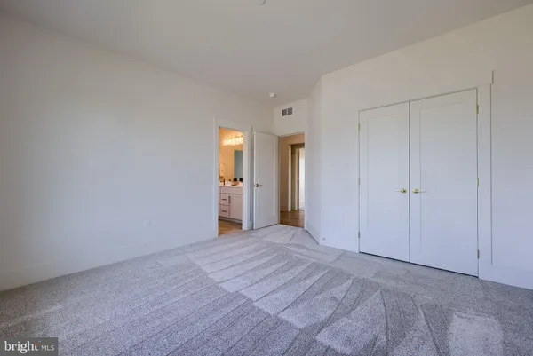 a view of an empty room with closet and a window