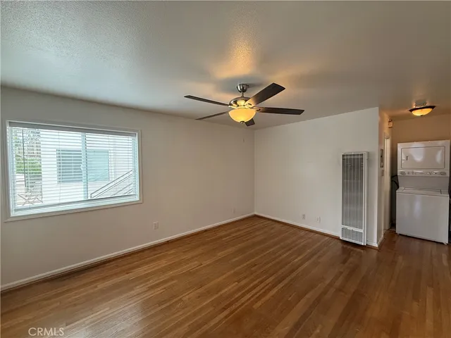 an empty room with wooden floor chandelier fan and windows