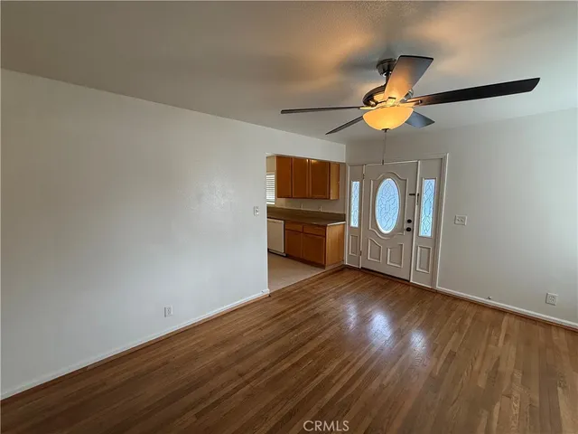 an empty room with wooden floor fan and windows