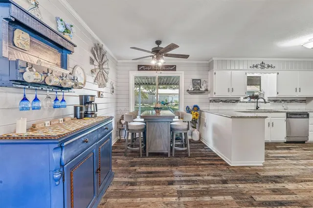 a kitchen with stainless steel appliances granite countertop a stove a sink dishwasher and a dining table with wooden cabinet