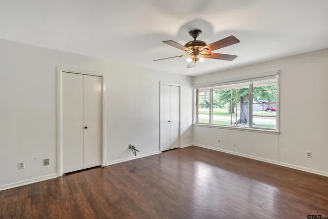 a view of empty room with wooden floor and fan