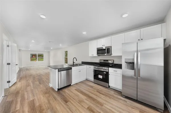 a kitchen with granite countertop a refrigerator stove top oven and sink