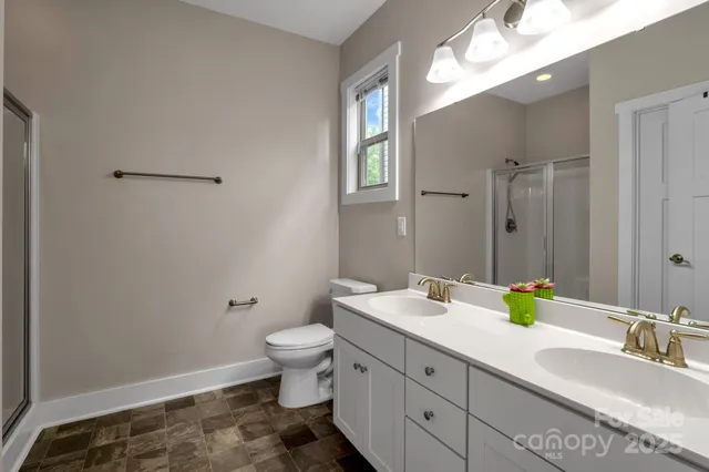 a bathroom with a double vanity sink toilet and a mirror