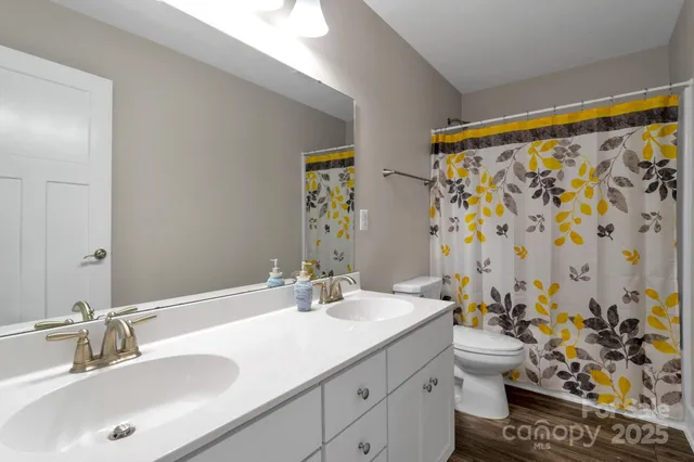 a bathroom with a granite countertop sink a toilet and shower curtain