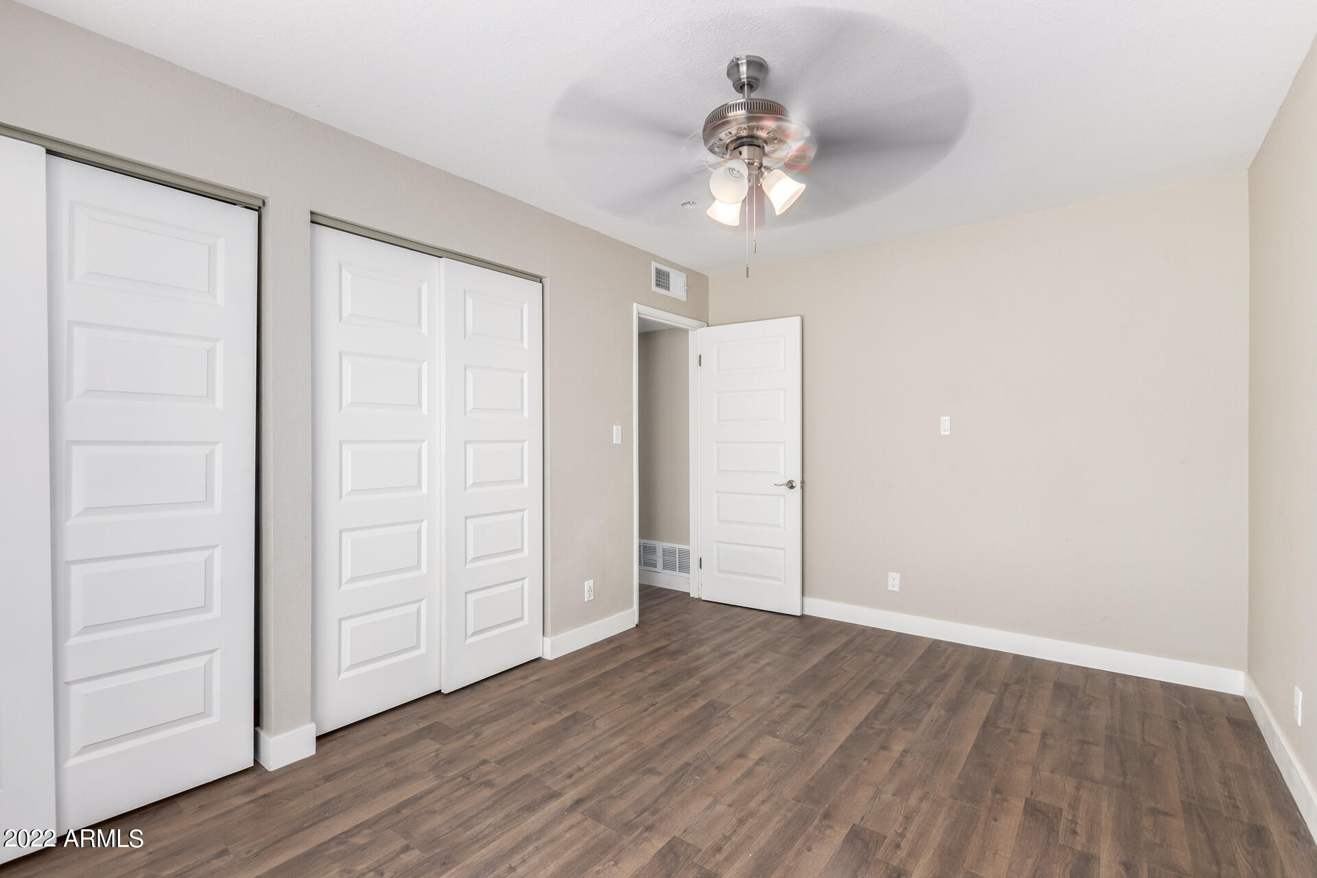 1036 East Butler Drive Phoenix, AZ 85020 - Photo 15 of 25 an empty room with wooden floor chandelier fan and closet area