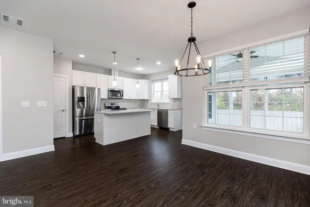 a kitchen with stainless steel appliances granite countertop a refrigerator a sink dishwasher a s stove top oven a large island with wooden floor and cabinets