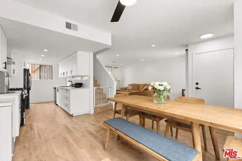 a kitchen with stainless steel appliances kitchen island granite countertop a refrigerator a stove a microwave oven a dining table and chairs with wooden floor