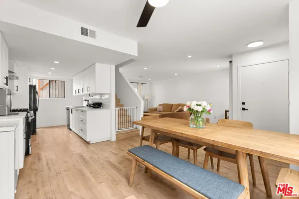 a kitchen with stainless steel appliances kitchen island granite countertop a refrigerator a stove a microwave oven a dining table and chairs with wooden floor