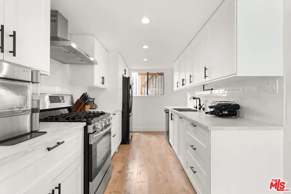 a kitchen with stainless steel appliances a sink stove and cabinets