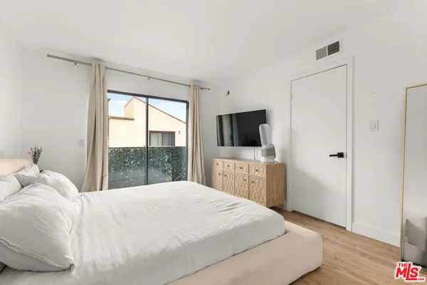 a bedroom with a large bed and a flat tv screen on dresser