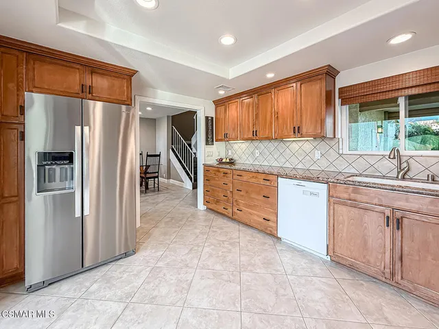a kitchen with granite countertop a refrigerator and cabinets