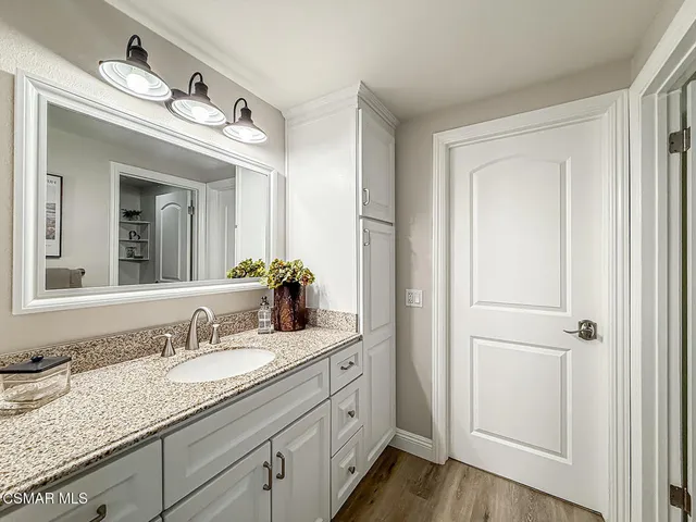 a en suite bathroom with a granite countertop sink and a mirror
