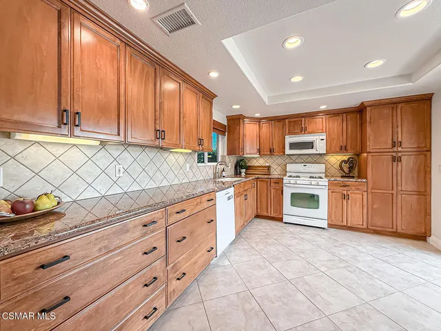 a kitchen with granite countertop white cabinets and stainless steel appliances