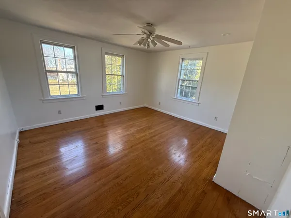 a view of an empty room with wooden floor and a window