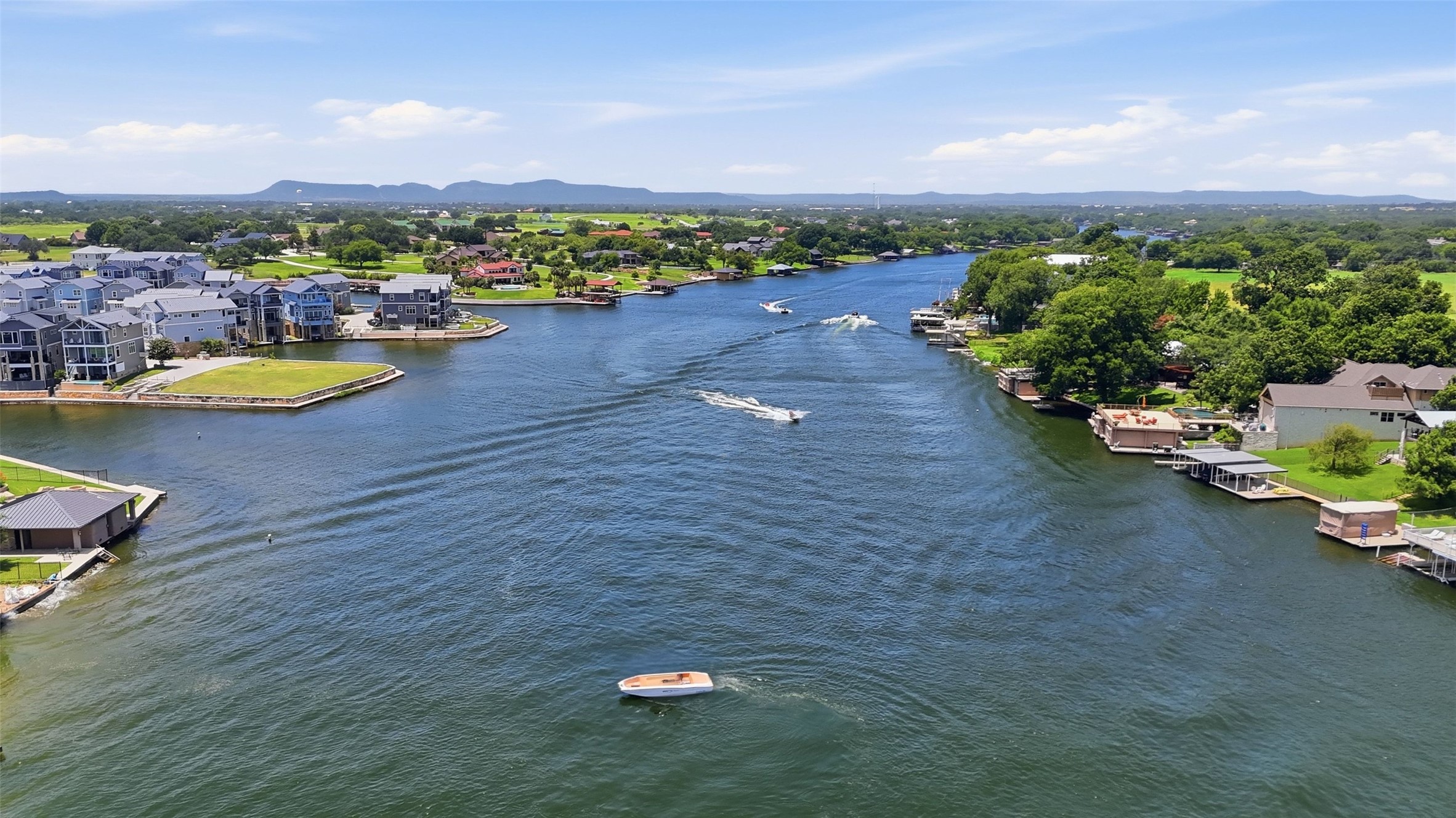 141 Perry Lane Kingsland, TX 78639 - Photo 40 of 40 A picturesque waterfront community awaits, with homes nestled along the serene river and scenic distant mountains.