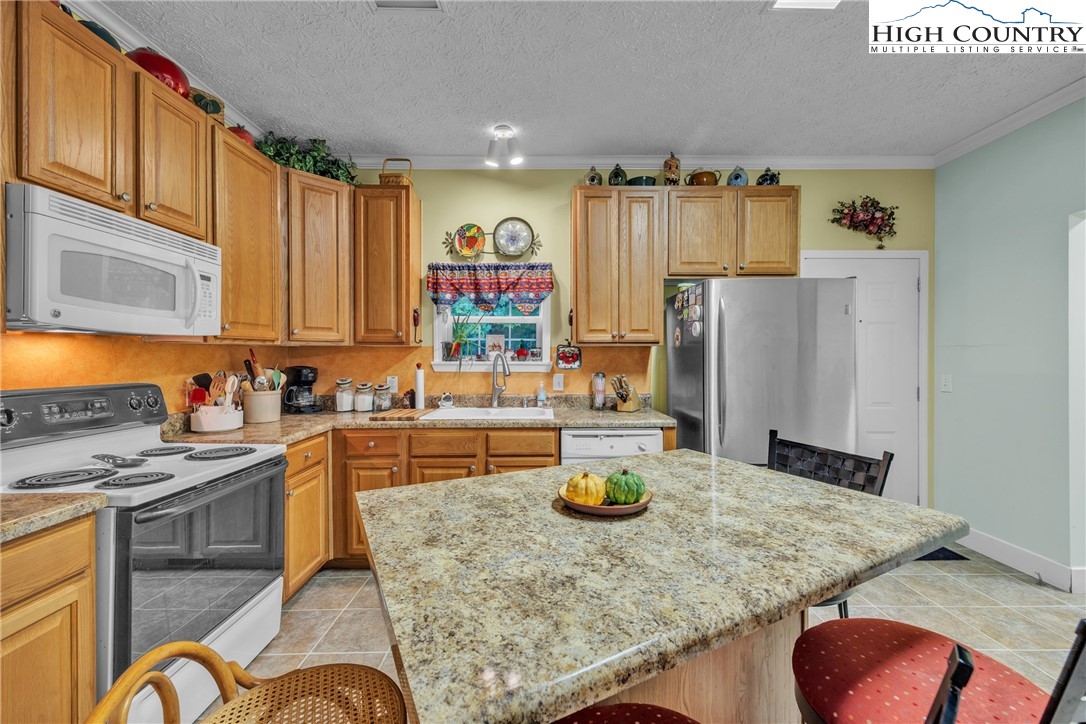 3786 Peak Road Creston, NC 28615 - Photo 5 of 31 a kitchen with a refrigerator a stove a sink dishwasher and wooden cabinets with wooden floor