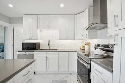a kitchen with white cabinets and appliances