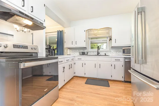 a kitchen with stainless steel appliances kitchen island granite countertop a sink window and cabinets