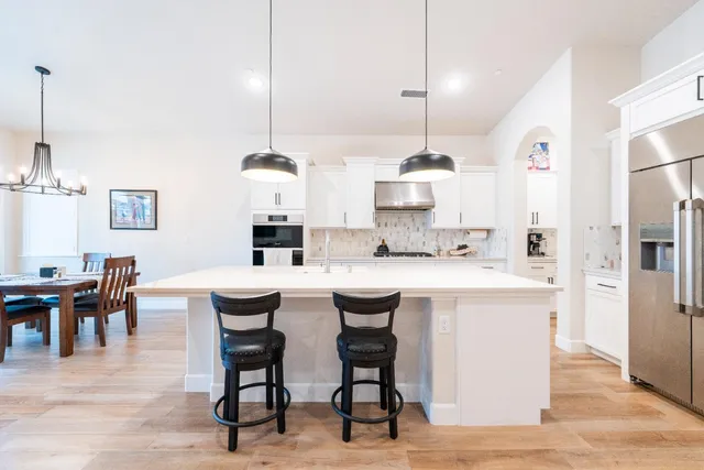 a large kitchen with kitchen island a stove a sink a dining table and chairs