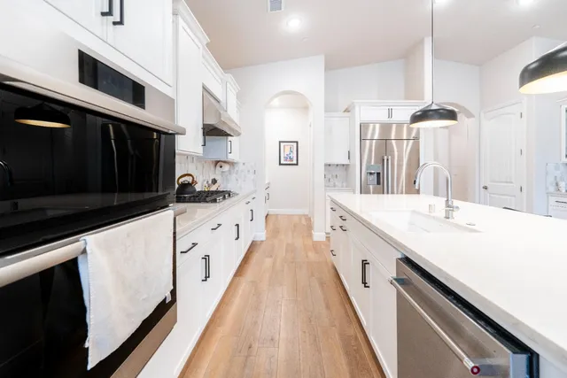 a kitchen with stainless steel appliances cabinets and a wooden floor