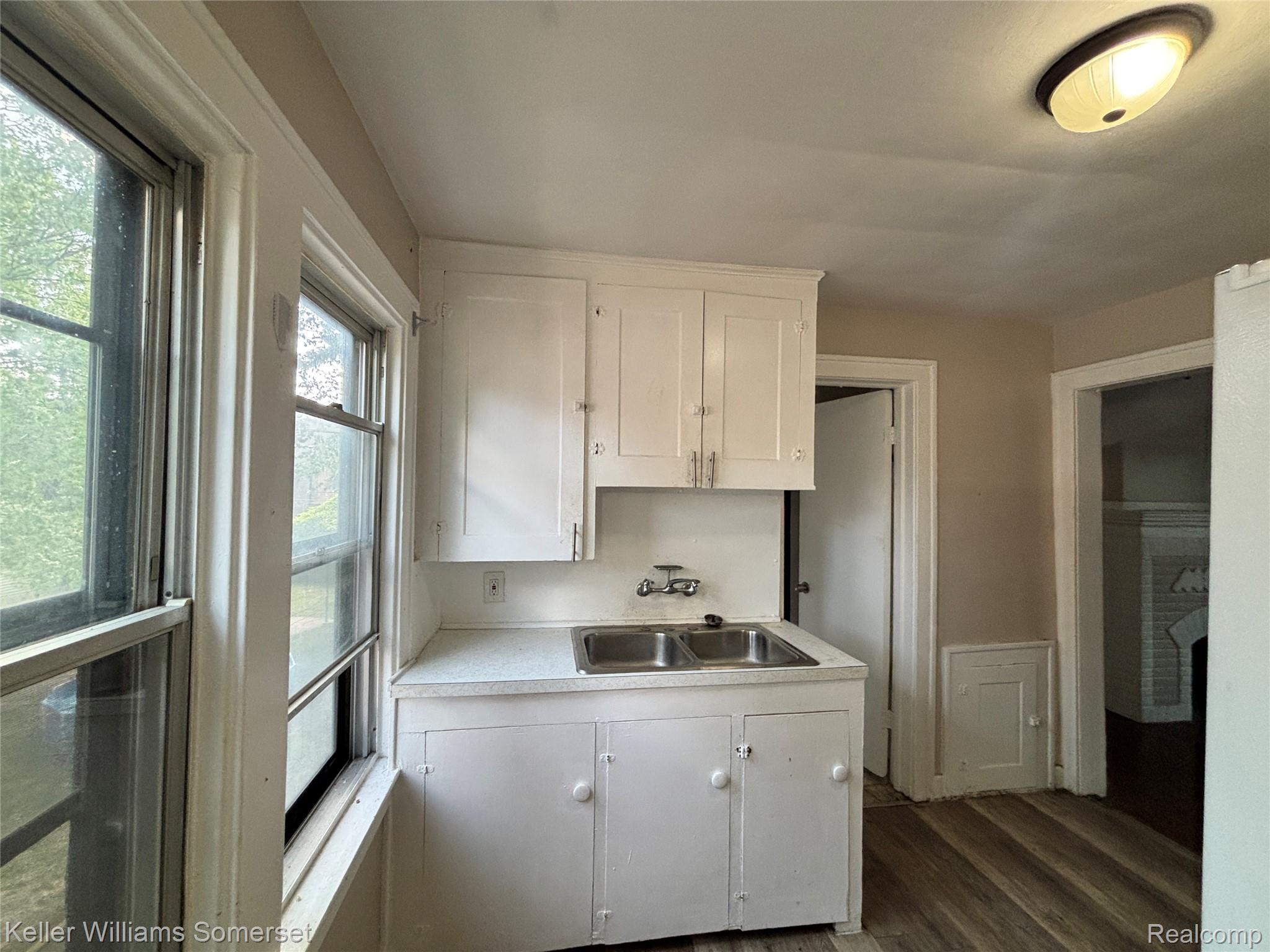5783 Yorkshire Road Detroit, MI 48224 - Photo 1 of 13 Kitchenette featuring white cabinetry, a double basin stainless steel sink, and speckled countertops
