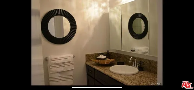 a bathroom with a granite countertop sink and a mirror