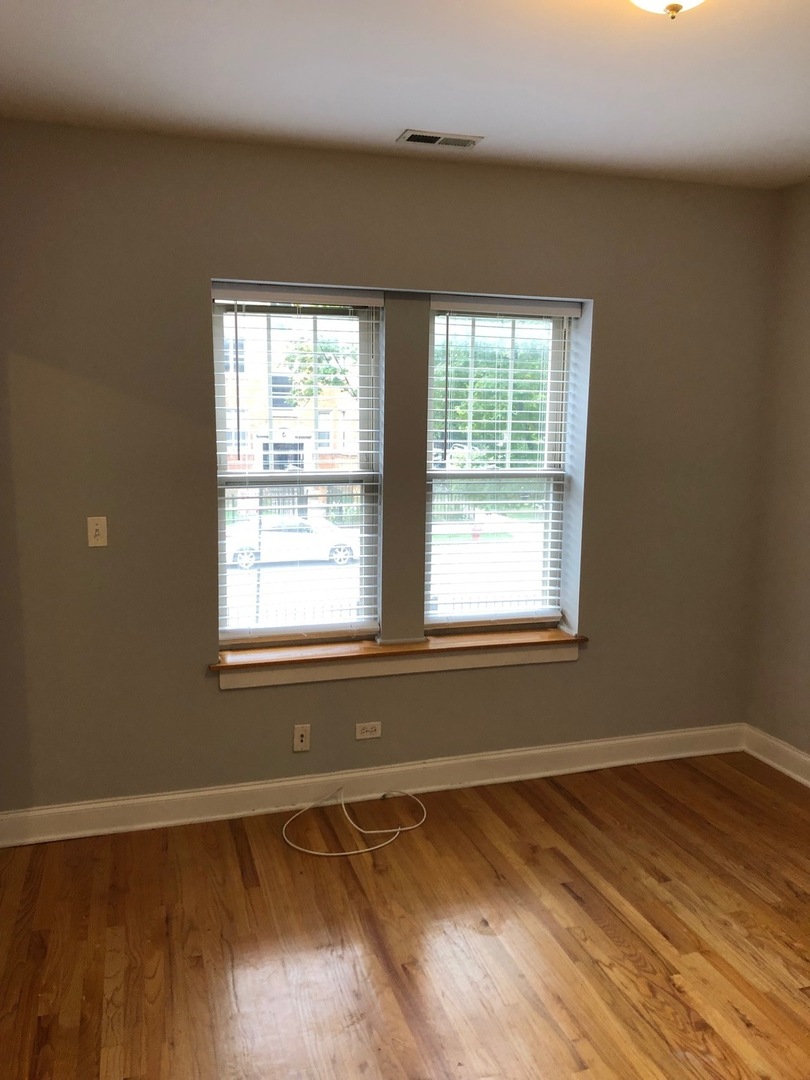 4855 North Drake Avenue, Unit 1 Chicago, IL 60625 - Photo 16 of 20 a view of an empty room with wooden floor and a window