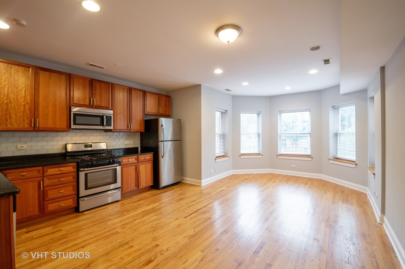 4855 North Drake Avenue, Unit 1 Chicago, IL 60625 - Photo 7 of 20 a large kitchen with stainless steel appliances granite countertop a stove a sink dishwasher a refrigerator and a microwave oven with wooden floor