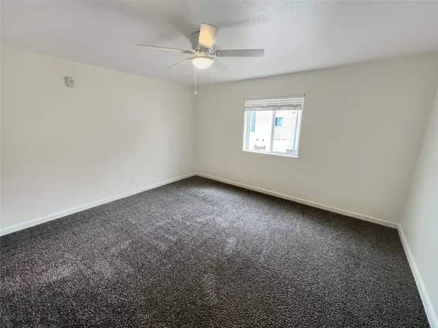 an empty room with a ceiling fan and a bathroom