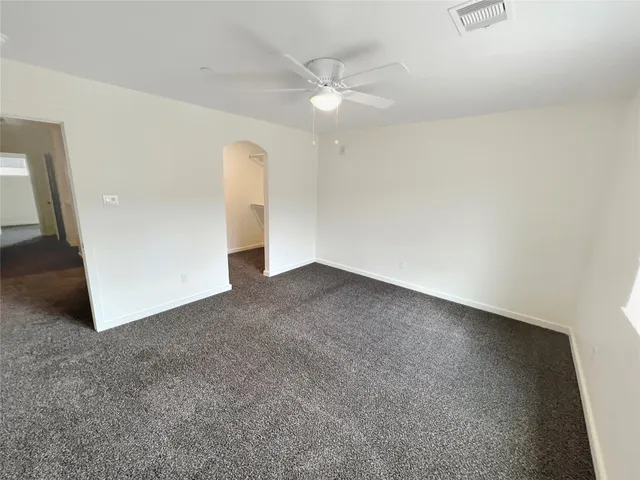 an empty room with a chandelier fan and windows