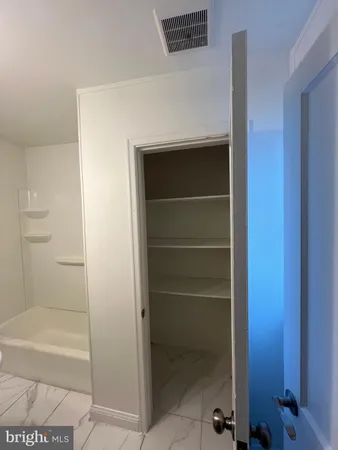 a view of a hallway with wooden floor and a bathroom