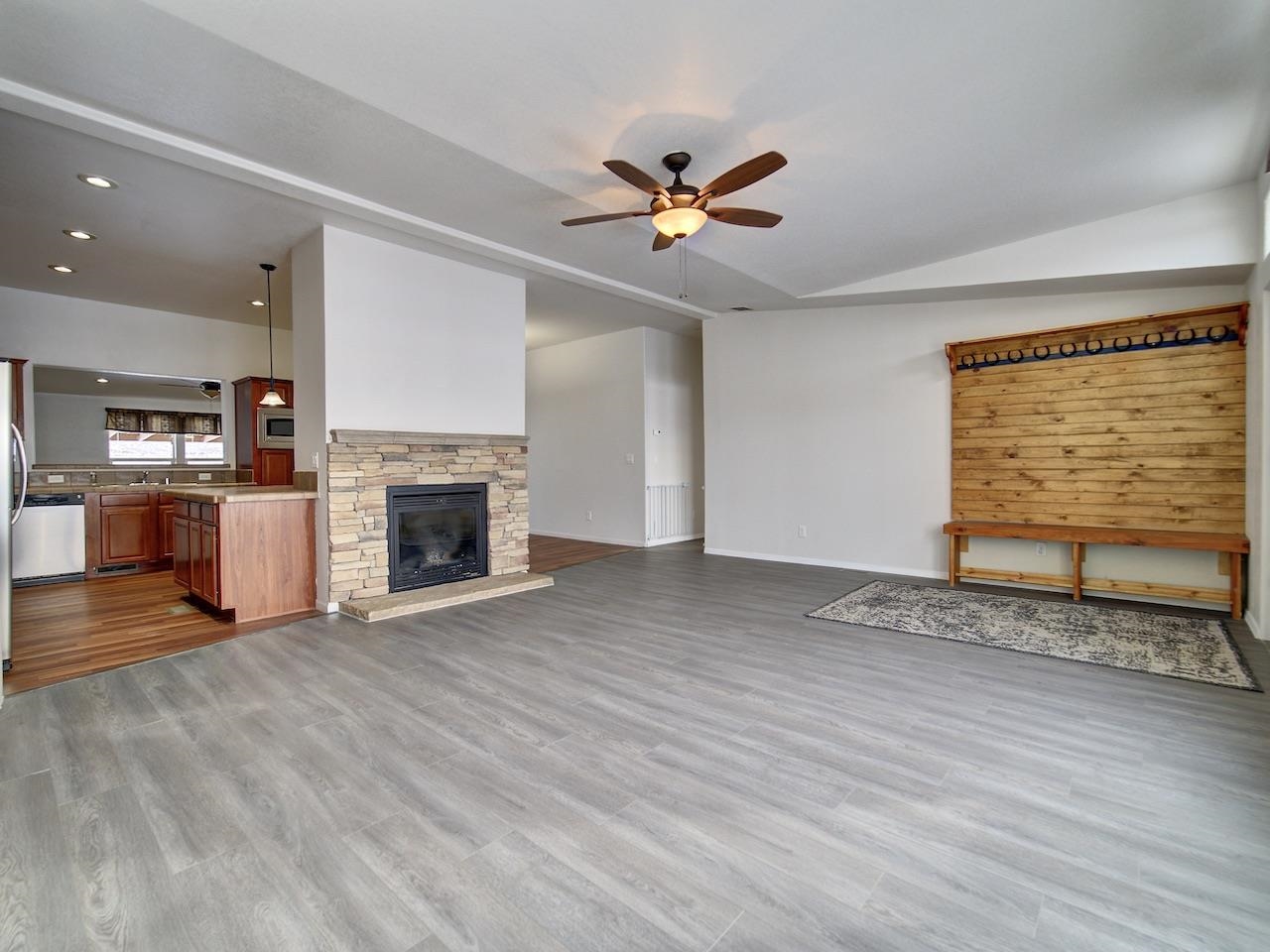 2423 16 Road Loma, CO 81524 - Photo 5 of 38 an empty room with wooden floor a ceiling fan a fireplace and windows