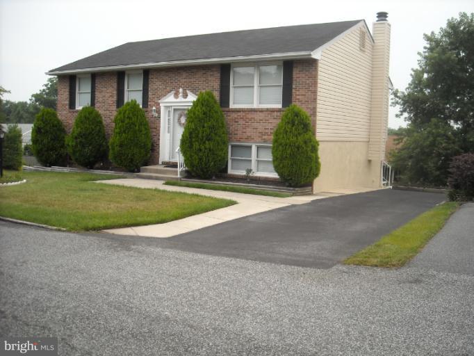 1215 Roxboro Road Rosedale, MD 21237 - Photo 13 of 29 a view of a brick house with a yard and large trees