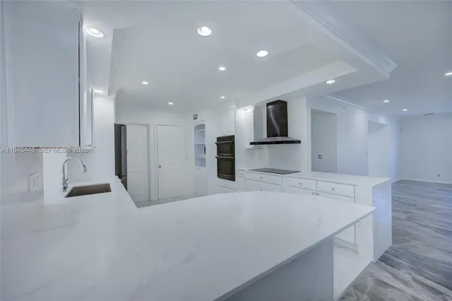 a large white kitchen with kitchen island a sink stainless steel appliances and cabinets