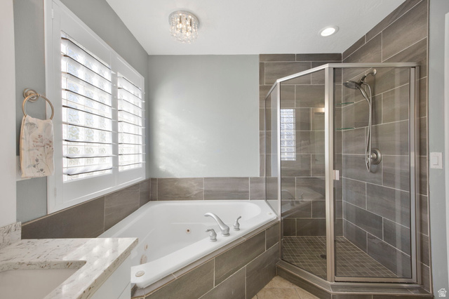 1440 West 100 South Virgin, UT 84779 - Photo 22 of 45 Bathroom featuring a corner soaking tub, walk-in shower with glass enclosure, tiled walls, plantation shutters, and a crystal flush mount light fixture