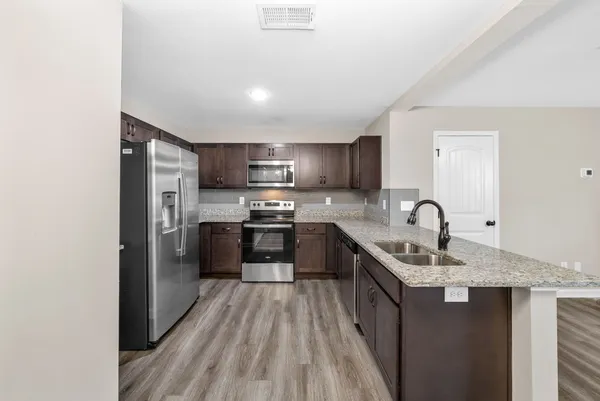 a kitchen with stainless steel appliances granite countertop a sink stove refrigerator and cabinets