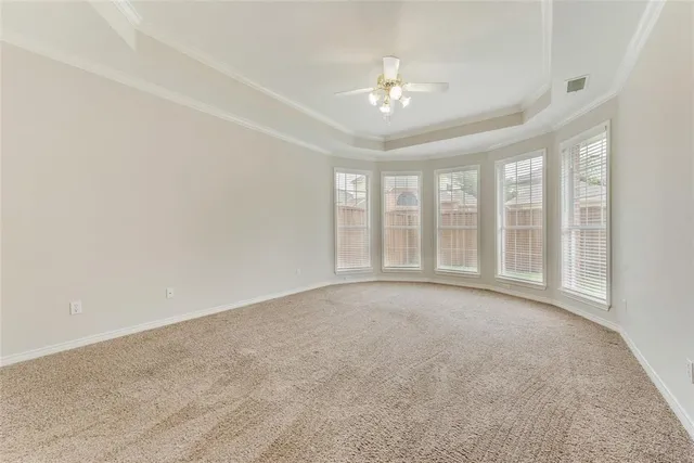 a view of an empty room with a chandelier fan and a large window