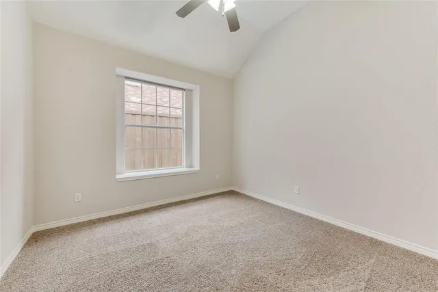 an empty room with chandelier fan and windows
