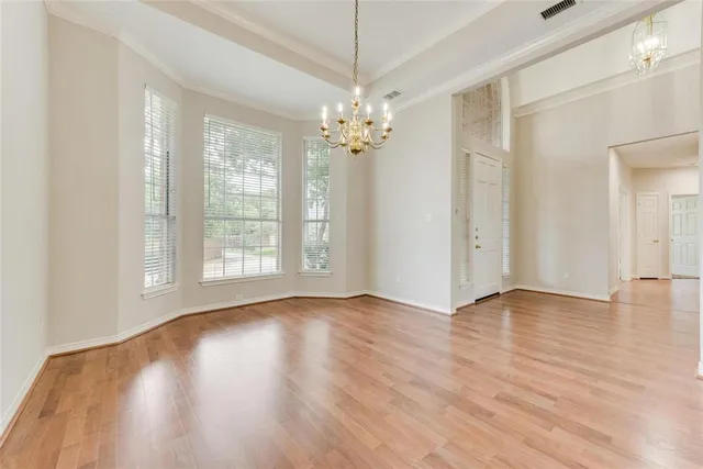 a view of an empty room with window and wooden floor
